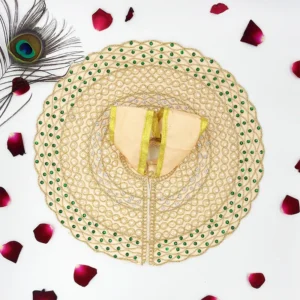 Flat lay of a cream and gold Laddu Gopal dress with pearl and embroidery details, set against a white background with rose petals.